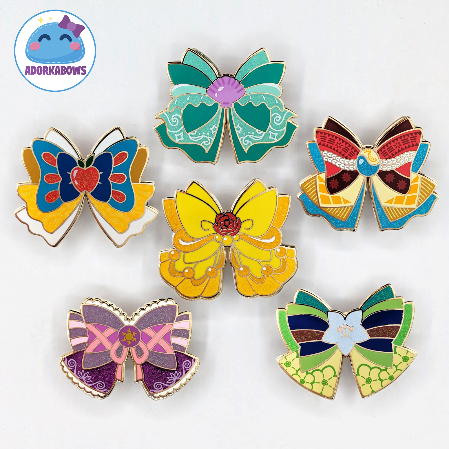 6 bow shaped enamel pins with designs inspired by various princesses and there's glitter on some parts